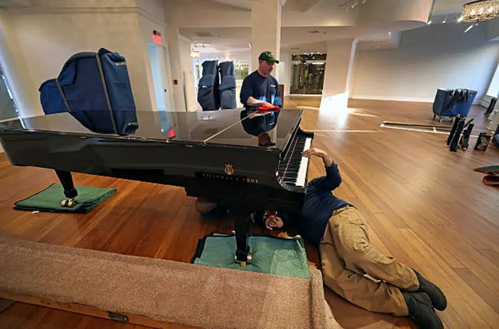 2 guys prepping a piano for a move